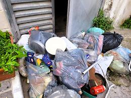 Cumuli di rifiuti abbandonati davanti all'uscita di sicurezza del supermercato