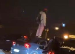 Un uomo di colore sul tetto di un'auto: la scena ripresa dai passanti