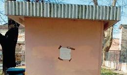 Bagno chiuso al parco, su una parete spunta un cartello di protesta
